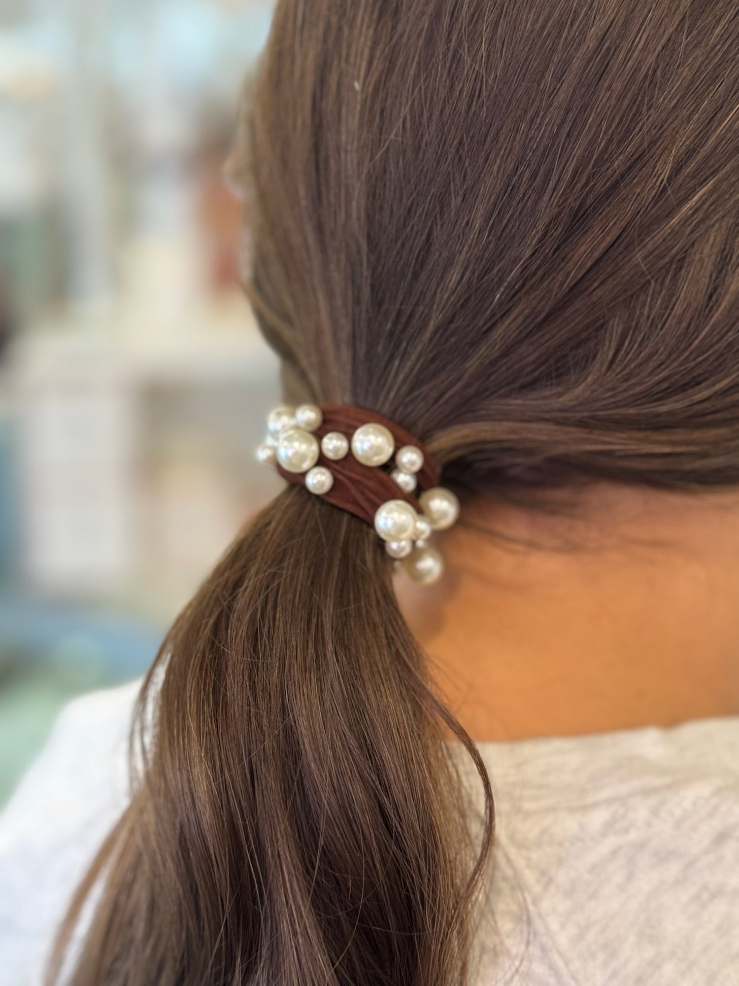Hair tie with pearls in a ponytail against a blurred background