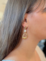 Gold earring with a pearl on a blurred background