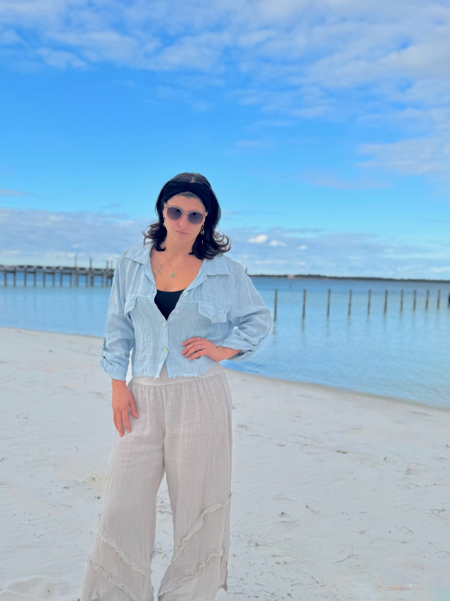 Person standing on a beach with a blue sky and ocean in the background