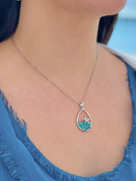Teardrop-shaped necklace with a star pendant on a person wearing a blue top.