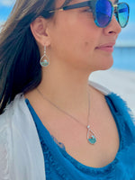 Person wearing dangly silver starfish earrings with blue accents, and a matching necklace.