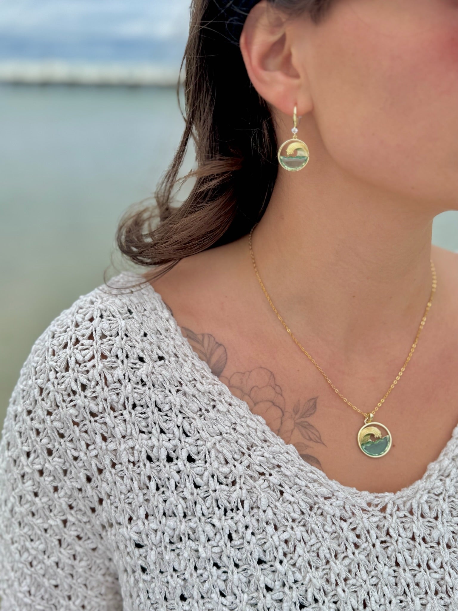Person wearing a gold necklace and earrings with a scenic background