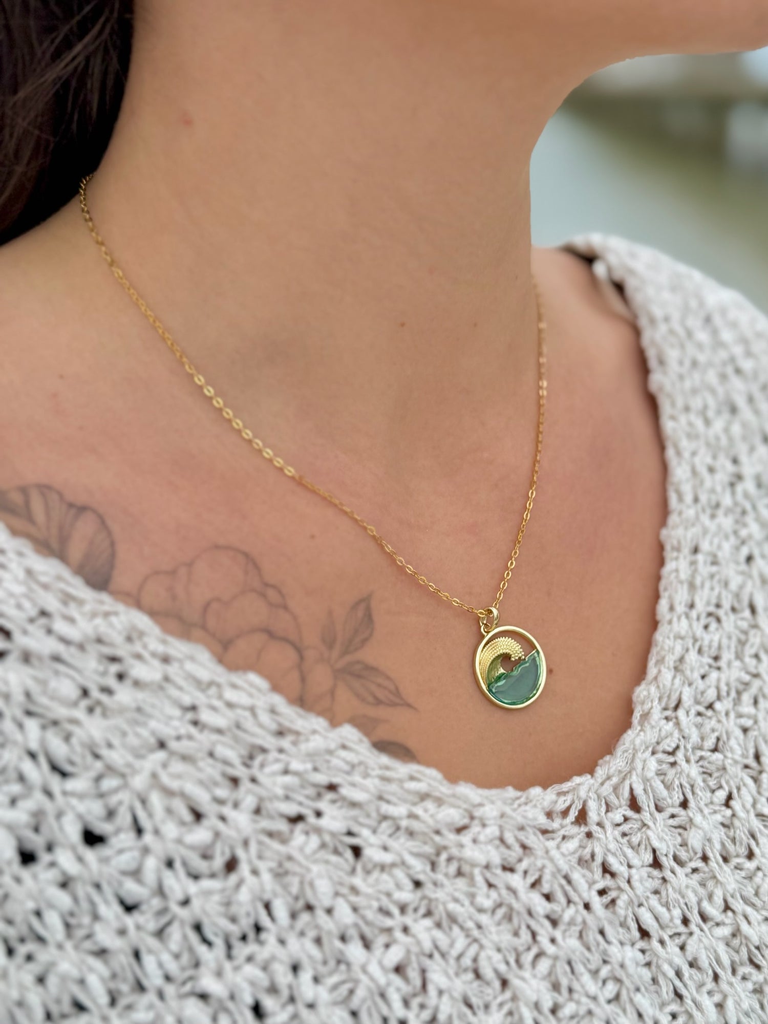 Necklace with a pendant worn by a person, close-up on the neck and shoulder.