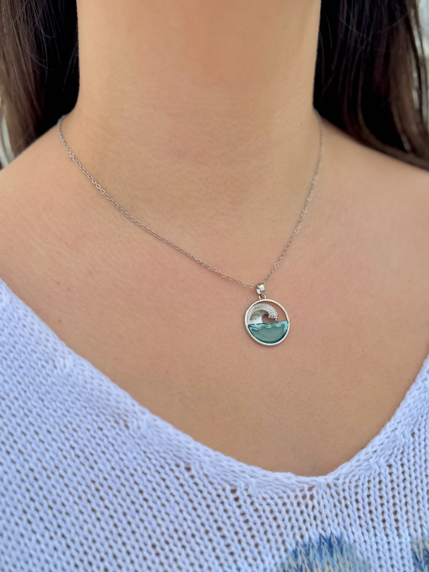 Necklace with a pendant featuring a scenic design worn by a person in a light blue top.