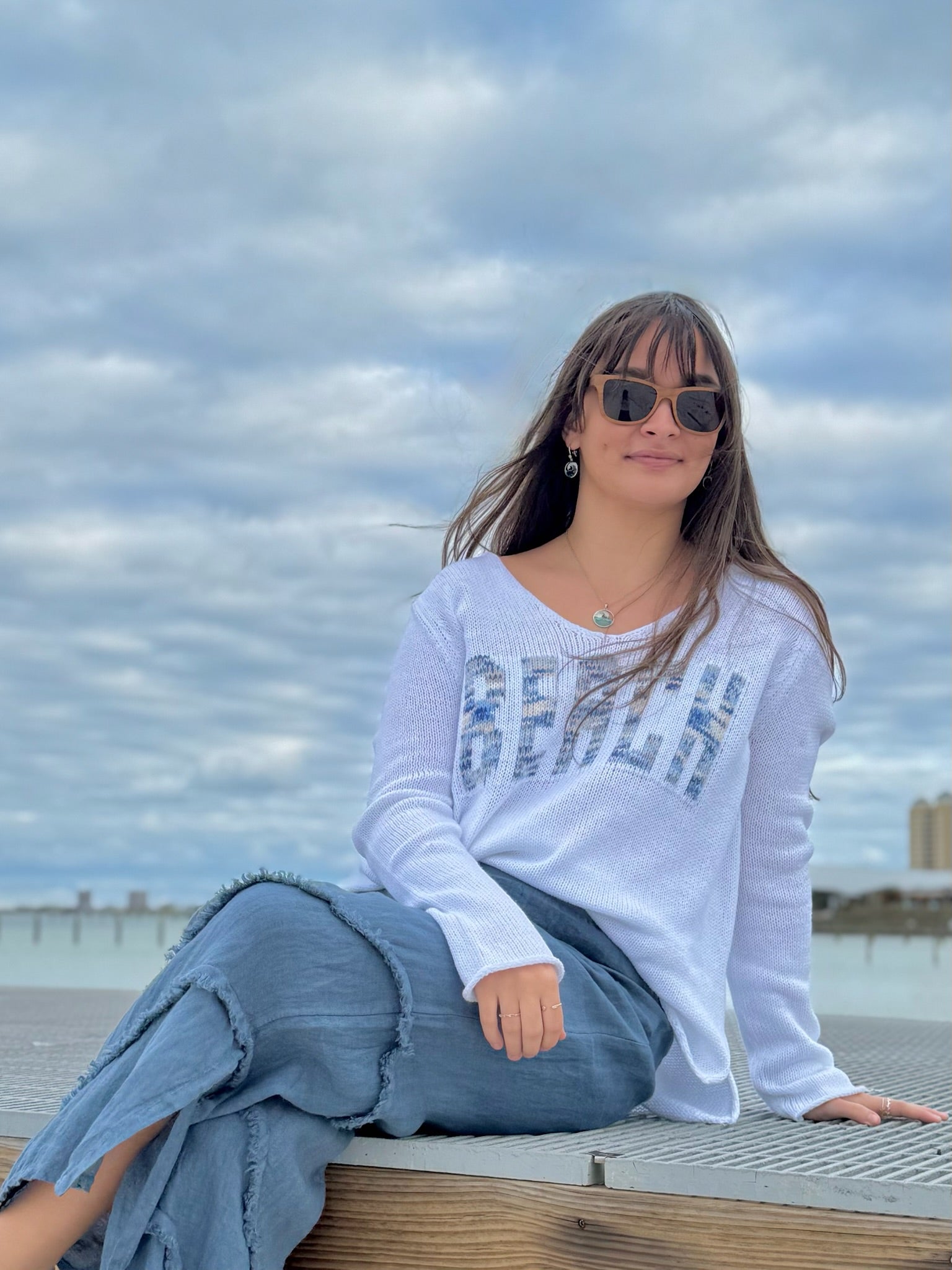 Woman sitting outdoors with a cloudy sky background