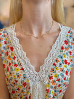 Daisy Floral Necklace in beige with gold-tone chain and beaded clusters on models neck 