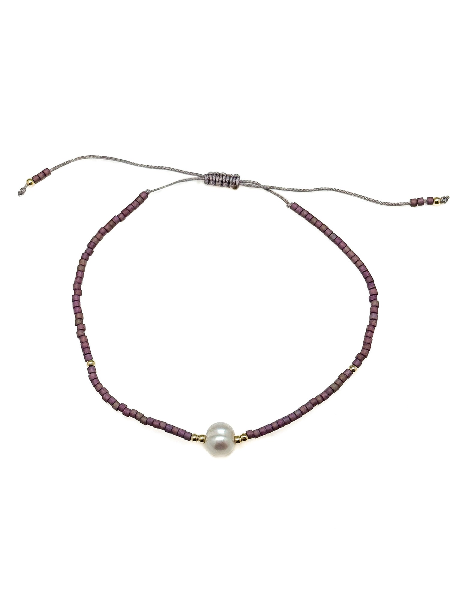 Bracelet with purple beads and a pearl on a white background