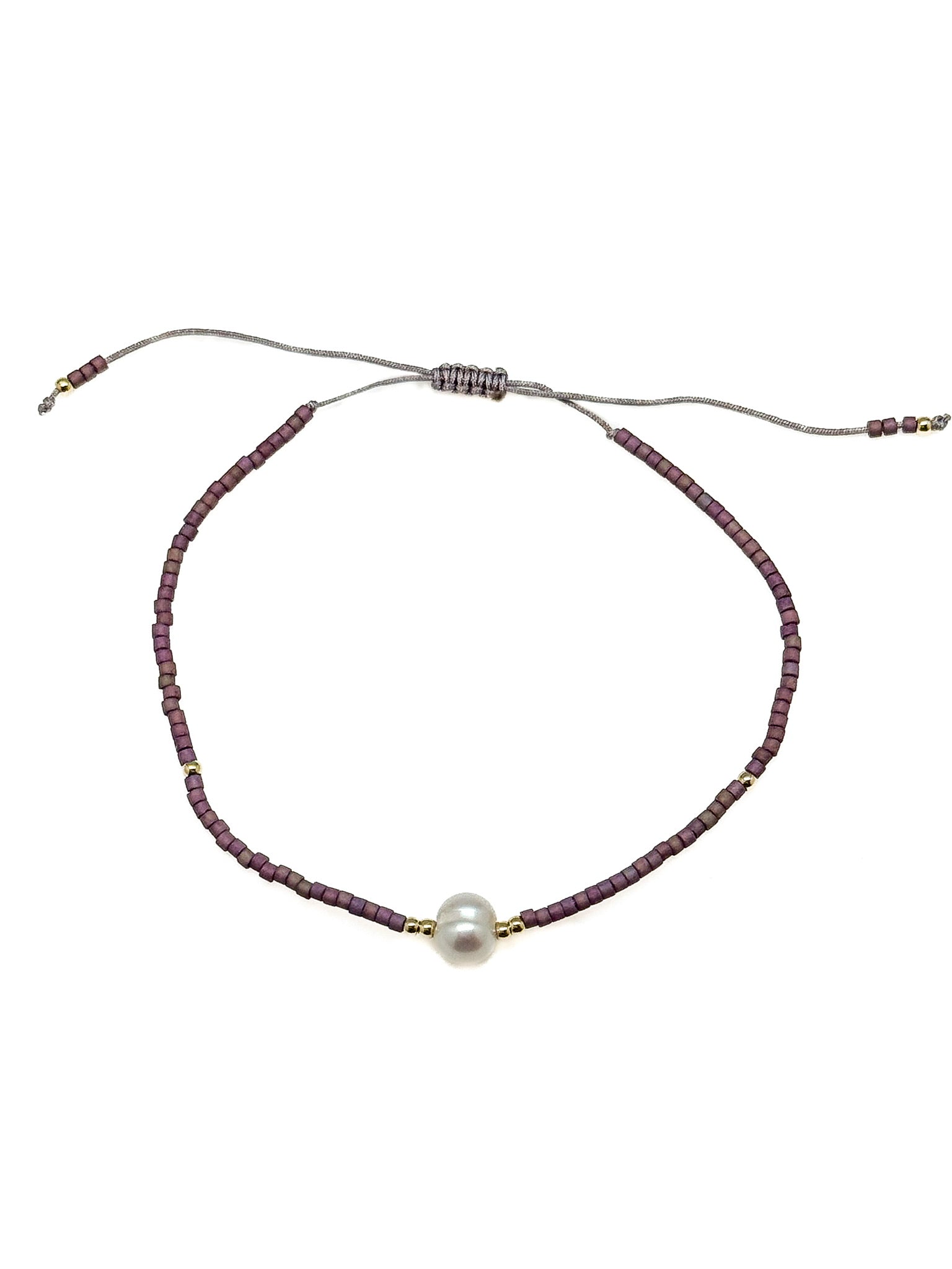 Bracelet with purple beads and a pearl on a white background