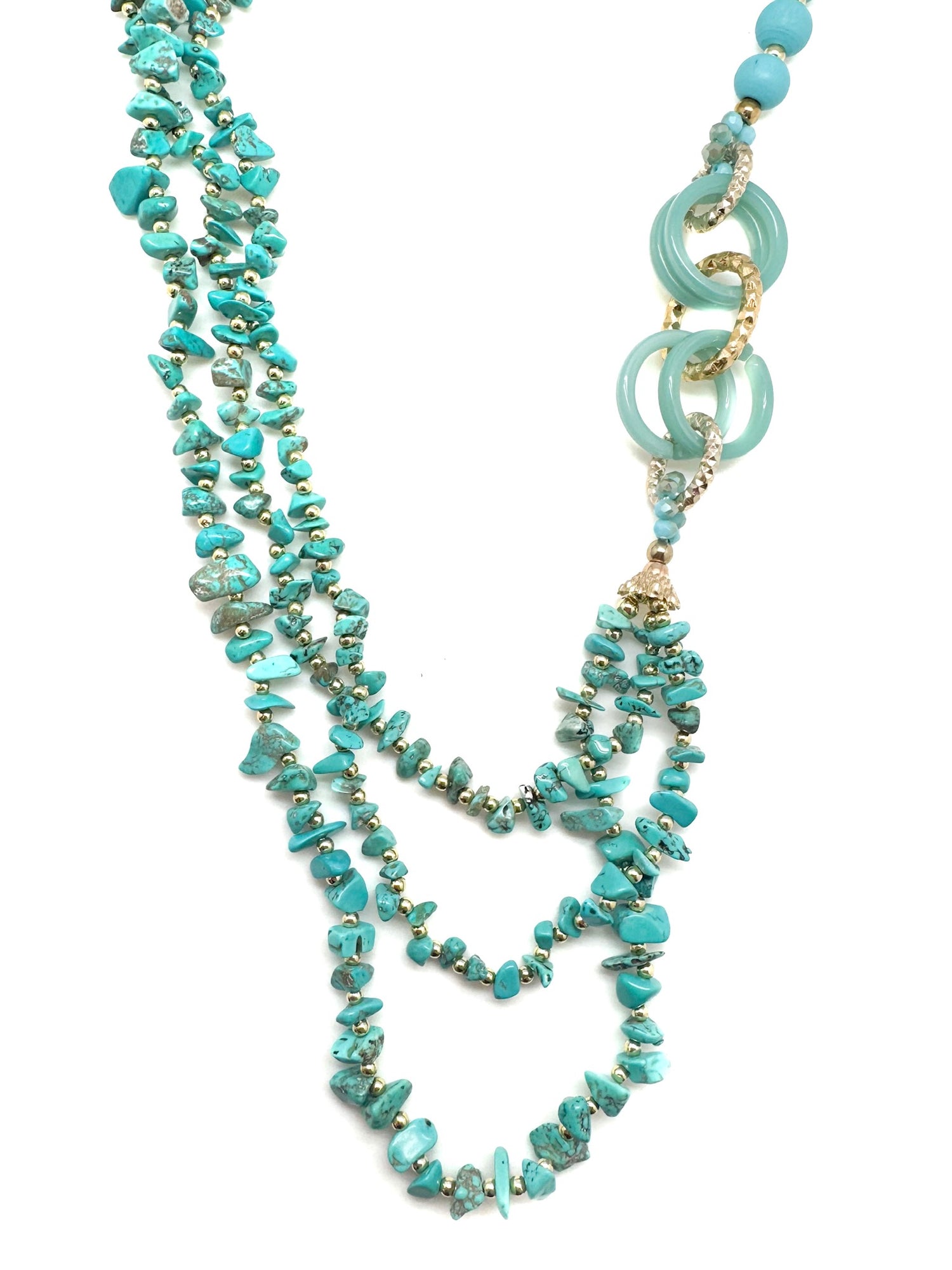 Layered turquoise stone chip necklace with gold accents and resin statement rings, displayed on white background.