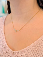 Gold necklace with a small pendant on a person wearing a pink top.