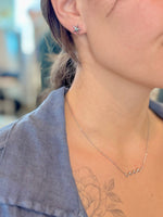 Close-up of a person wearing a star-shaped earring and a delicate necklace with a blurred background.