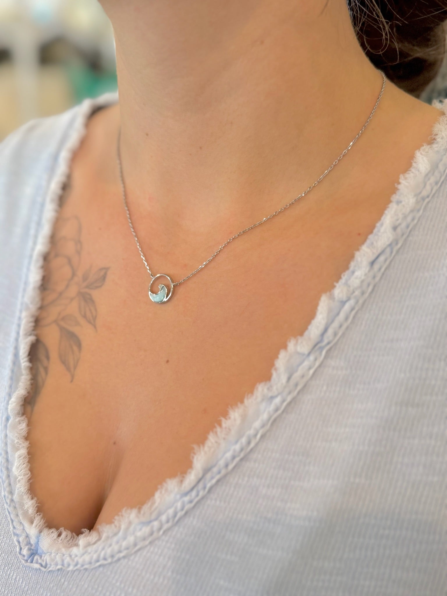sterling silver larimar wave necklace worn at the collarbone, shown on an adjustable chain.