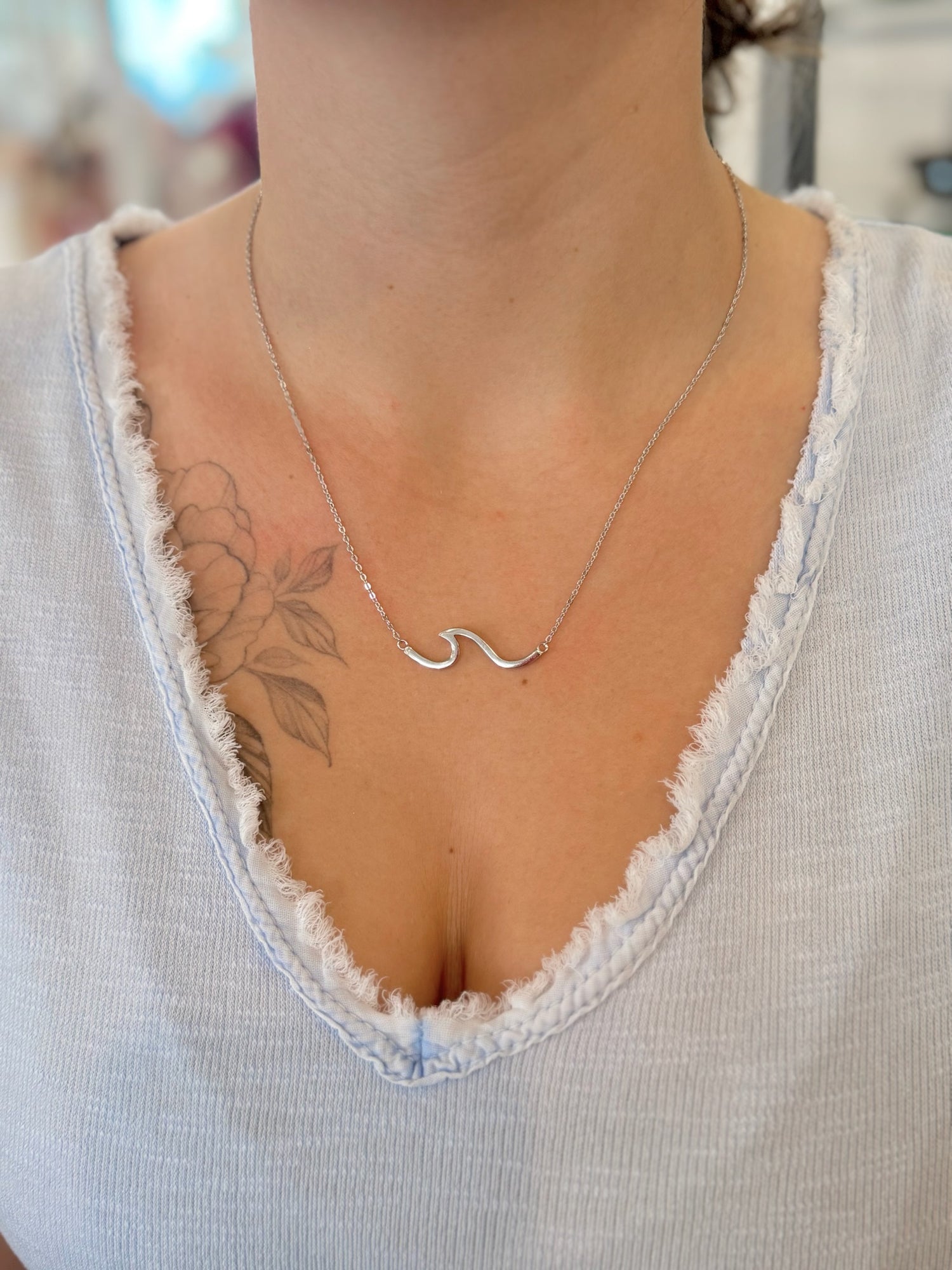 sterling silver wave necklace worn at the collarbone on an adjustable fine chain.