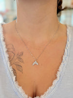 sparkly sterling silver dolphin tail pendant necklace worn with a V-neck top, showing length and fit.