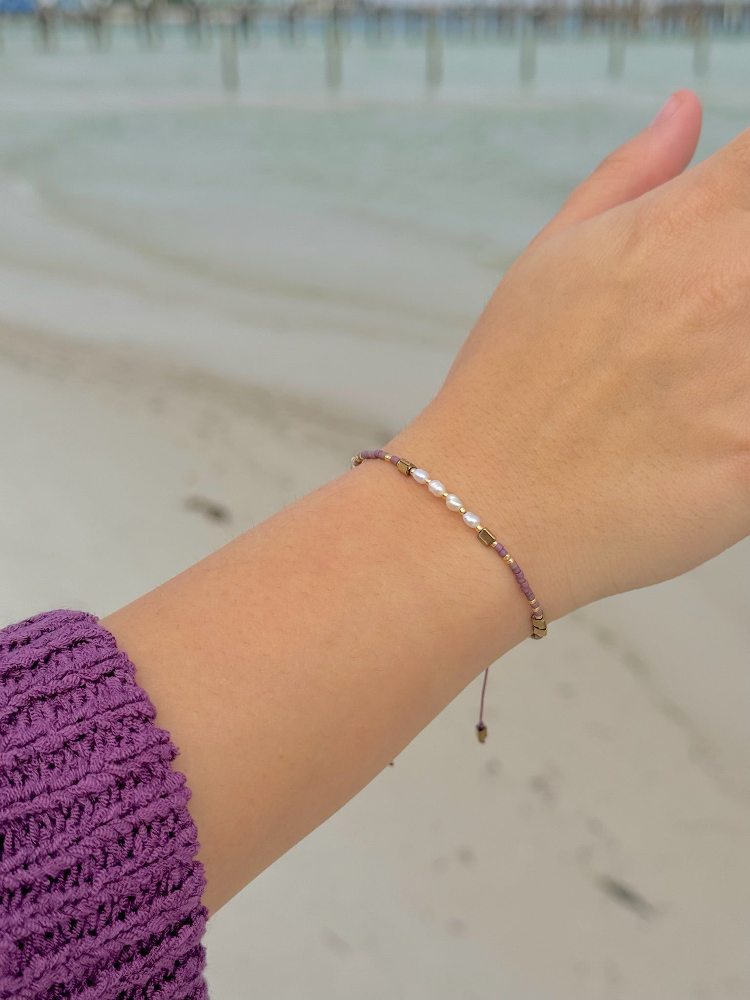 Hand wearing a bracelet with a blurred beach background