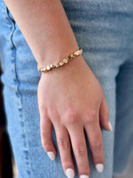 Gold bracelet on a wrist with a blurred denim background