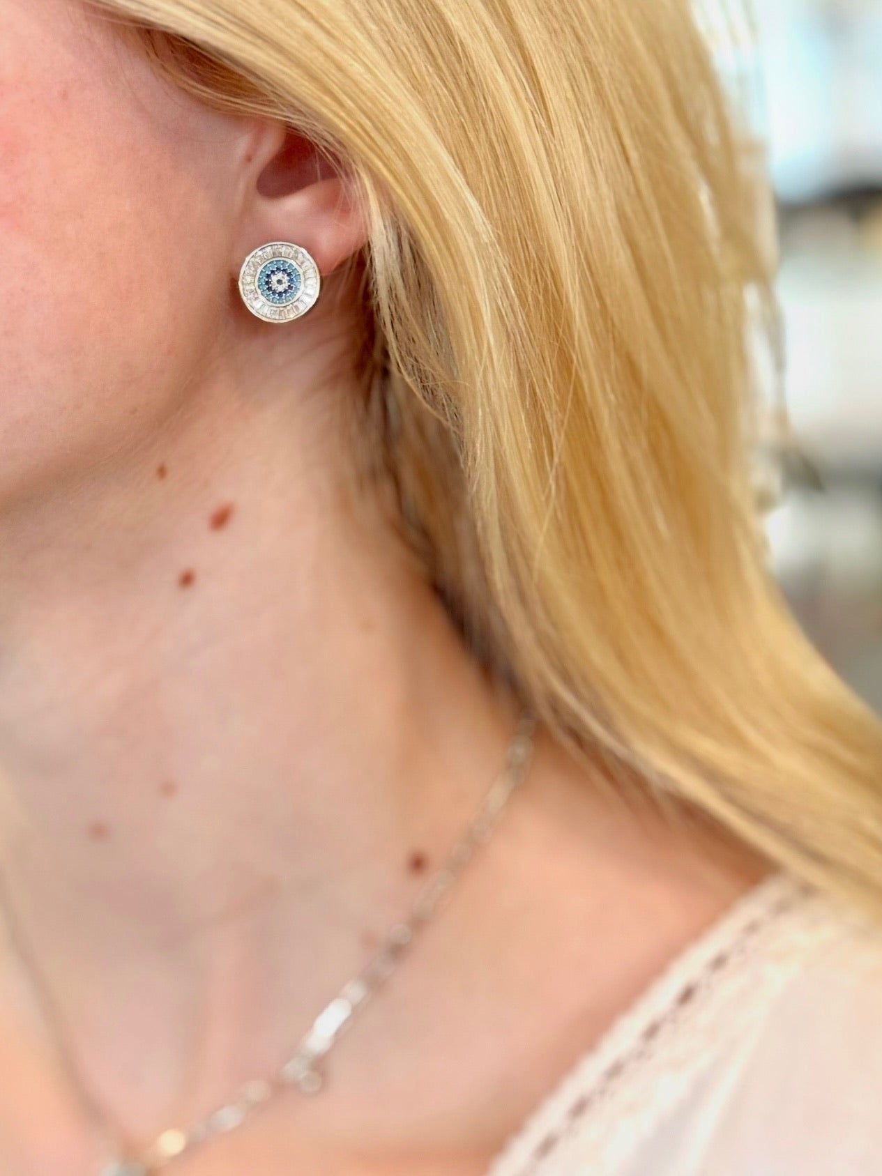 Close-up of a person wearing silver earrings with a blurred background