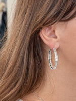 Woman wearing textured silver hoop earrings