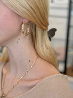 Woman wearing textured gold hoop earrings with a modern segmented design