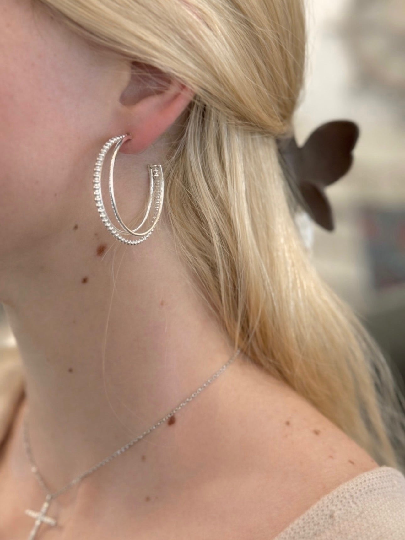 Woman wearing silver hoop earrings with subtle beaded detailing