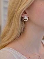Close-up of a person wearing silver earrings with a blurred background