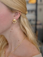 Woman wearing sculptural gold stud earrings with layered, softly rounded forms