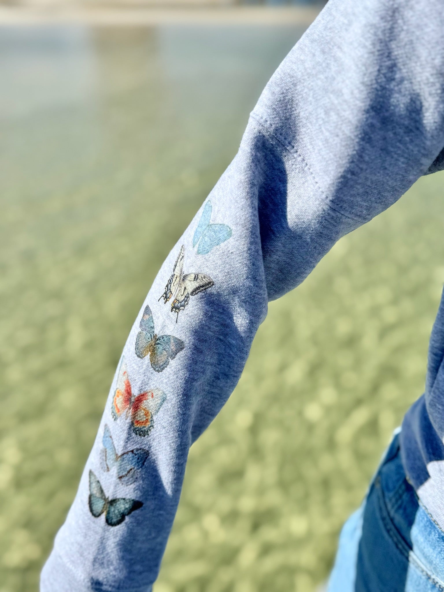 Close-up of a blue sleeve with butterfly designs against a blurred natural background
