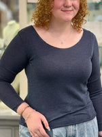 Woman wearing a navy long sleeve knit top with a scoop neckline and fitted silhouette.
