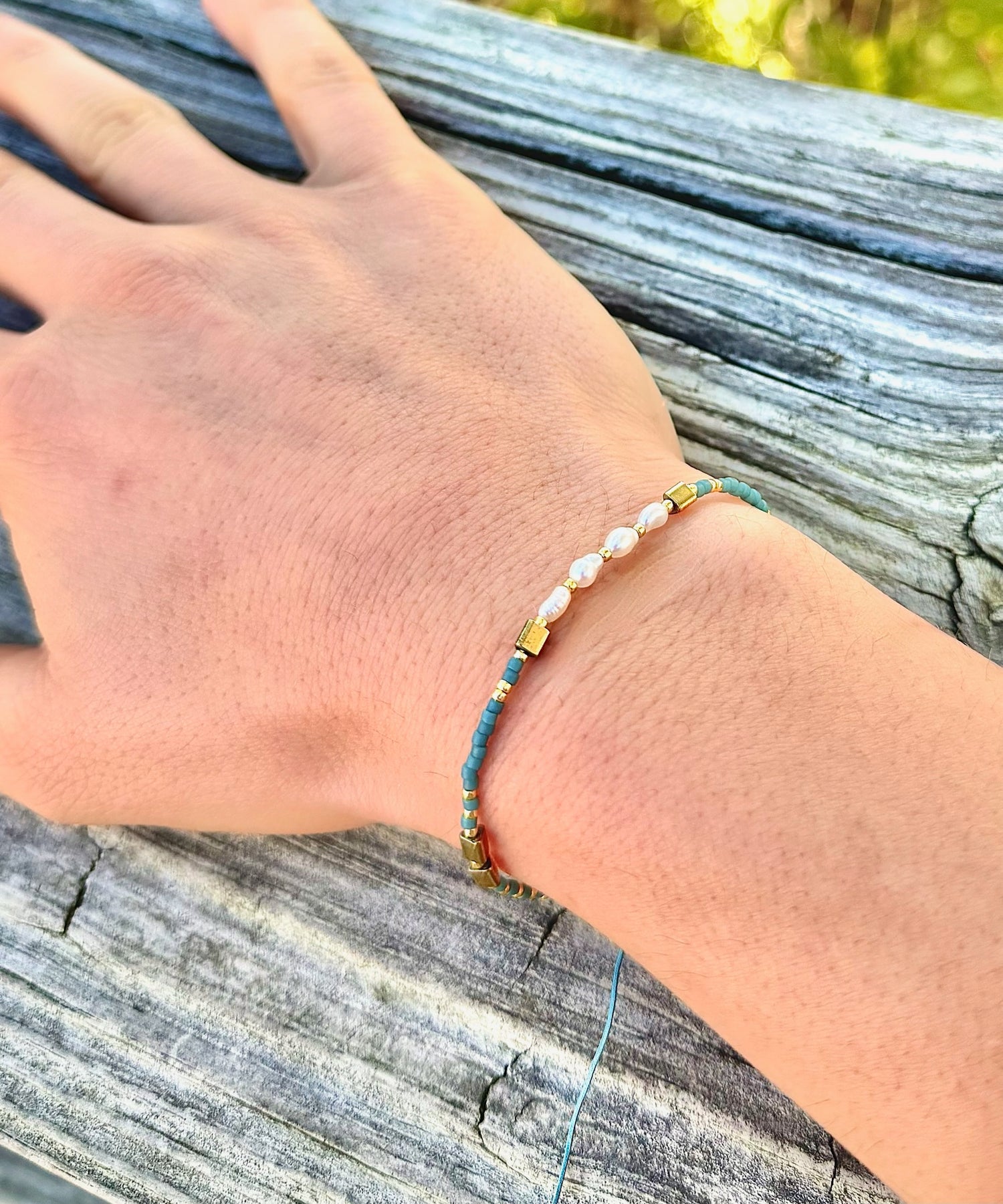 Gina Teal Pull Bracelet worn on wrist with teal beads, freshwater pearls, and gold-tone accents