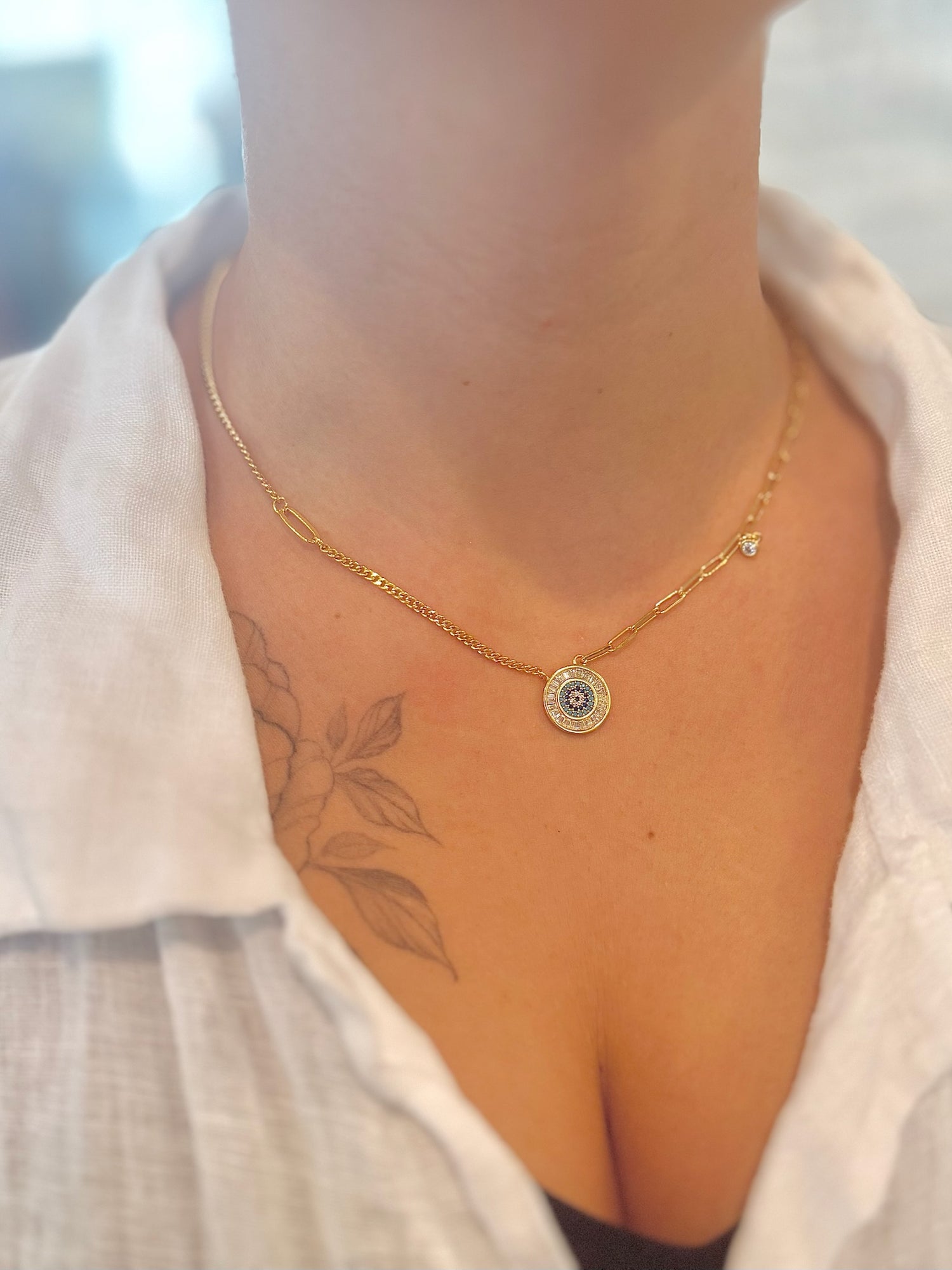 Gold necklace with a pendant worn by a person, blurred background