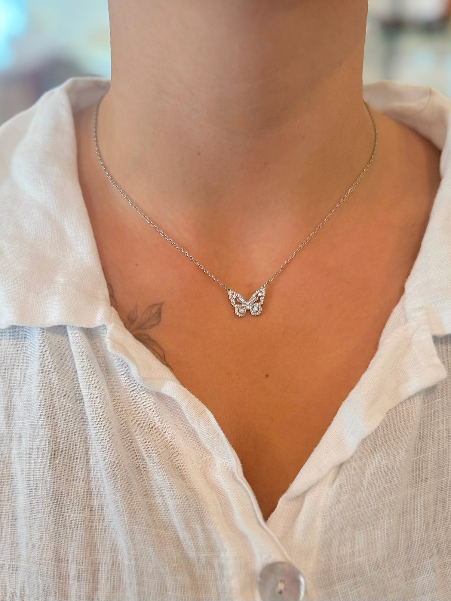Butterfly necklace worn by a person with a blurred background