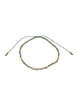 Adjustable bracelet featuring faceted gray labradorite gemstones, freshwater pearls, gold accent beads, and a sliding cord closure. Handmade with a delicate, coastal-inspired design perfect for everyday layering.