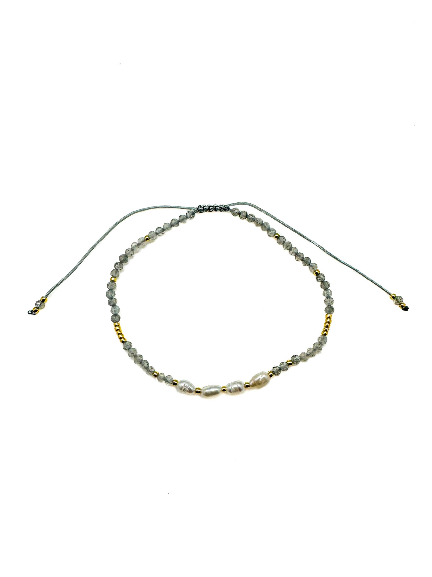 Adjustable bracelet featuring faceted gray labradorite gemstones, freshwater pearls, gold accent beads, and a sliding cord closure. Handmade with a delicate, coastal-inspired design perfect for everyday layering.