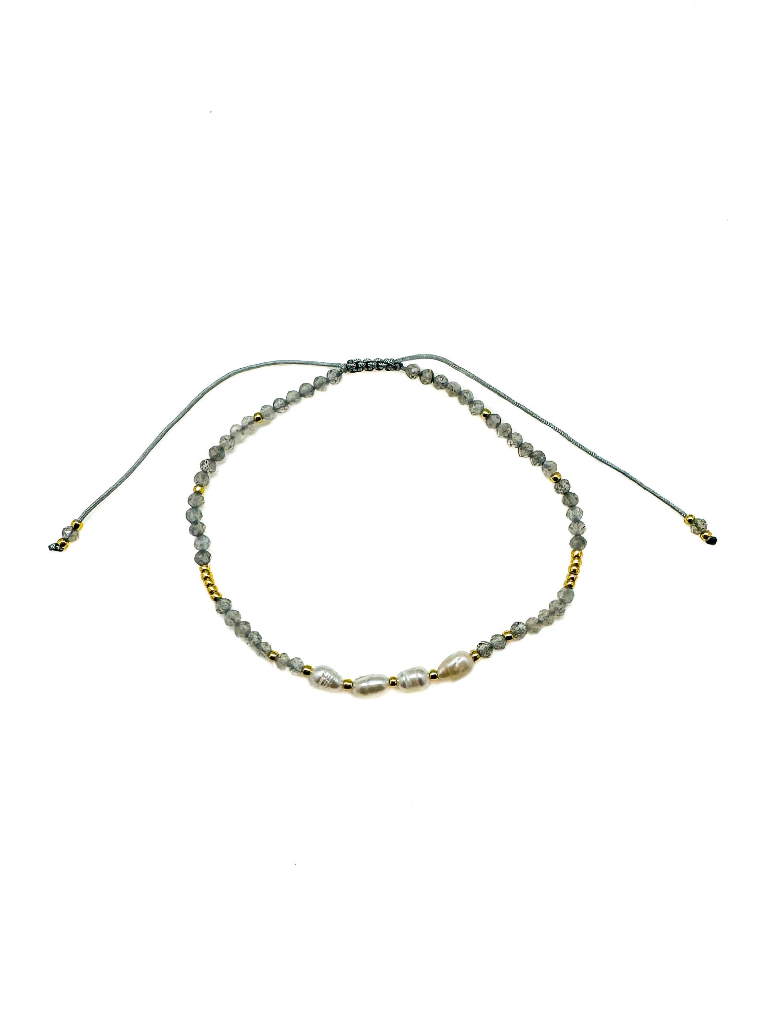 Adjustable bracelet featuring faceted gray labradorite gemstones, freshwater pearls, gold accent beads, and a sliding cord closure. Handmade with a delicate, coastal-inspired design perfect for everyday layering.