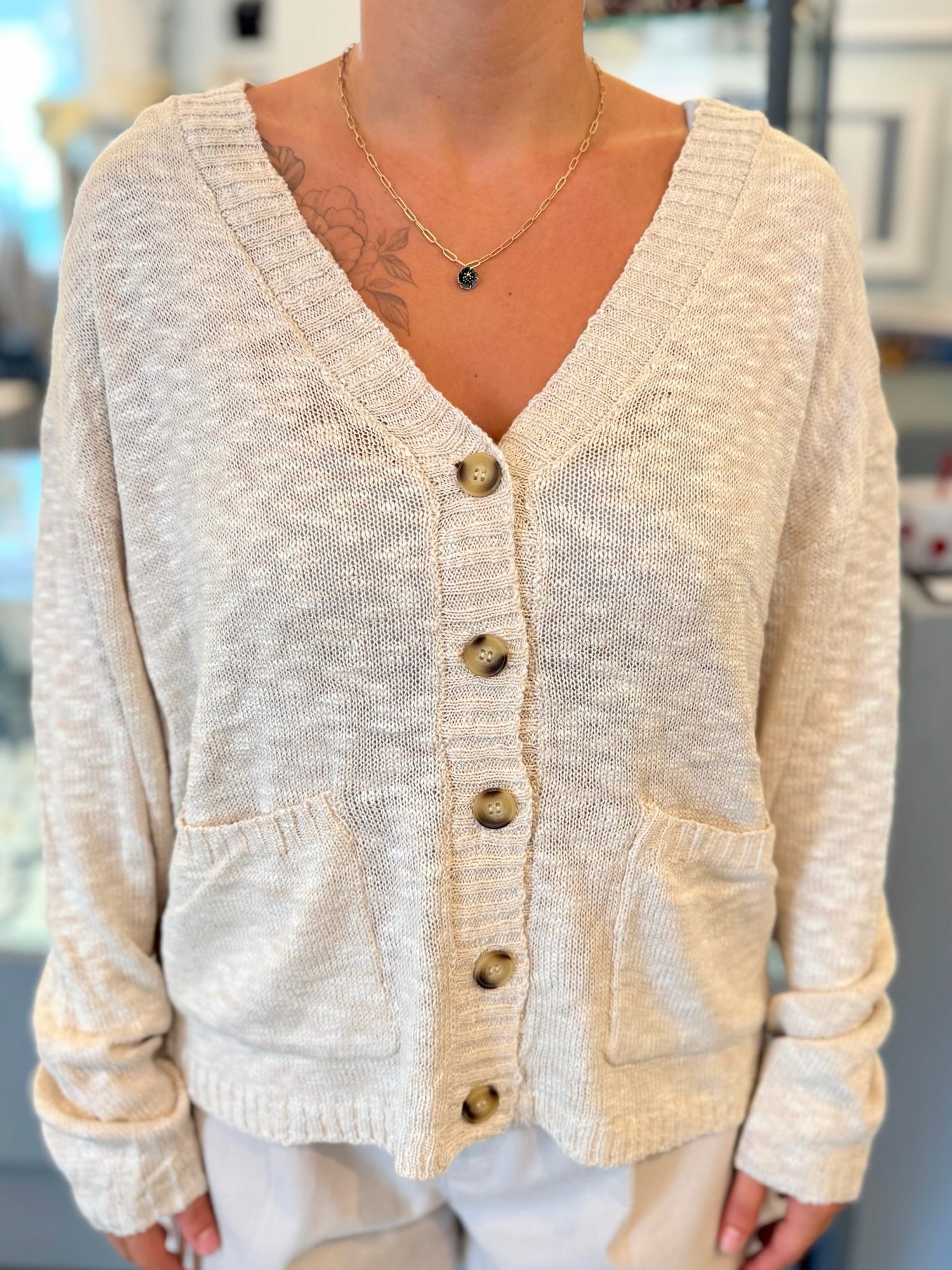 Beige cardigan worn by a person with a blurred background