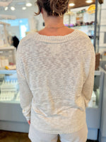 Person wearing a light gray sweater in an indoor setting
