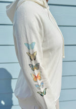 White hoodie with colorful blue butterfly designs on a light blue background
