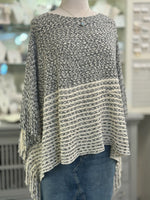 Knitted poncho on a mannequin in front of a store display.