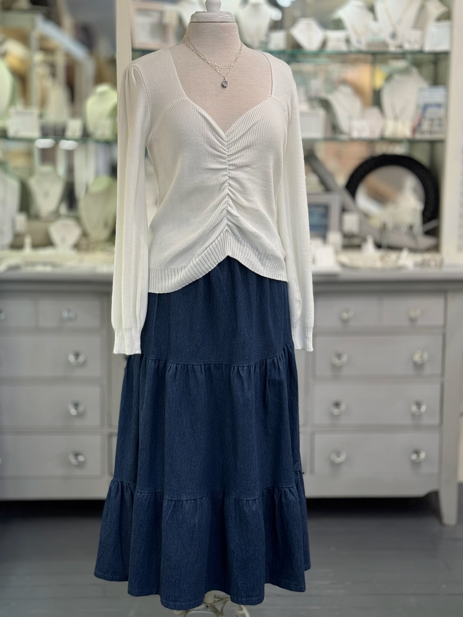 Mannequin wearing a white top and blue skirt in a store setting