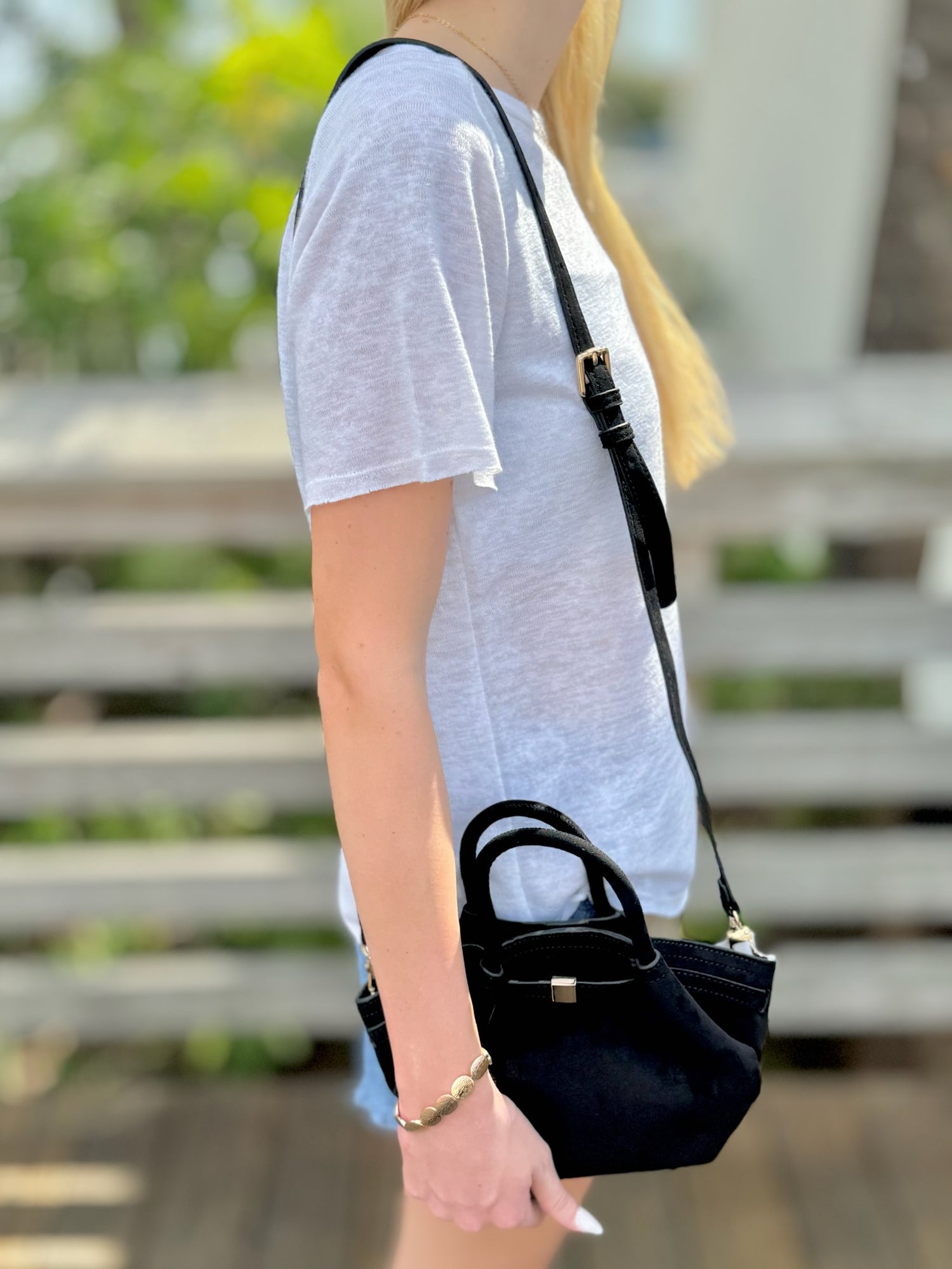 Person holding a black handbag with a blurred background