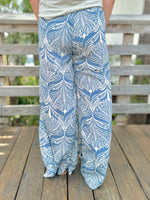 Blue and white patterned pants worn by a person on a wooden deck.