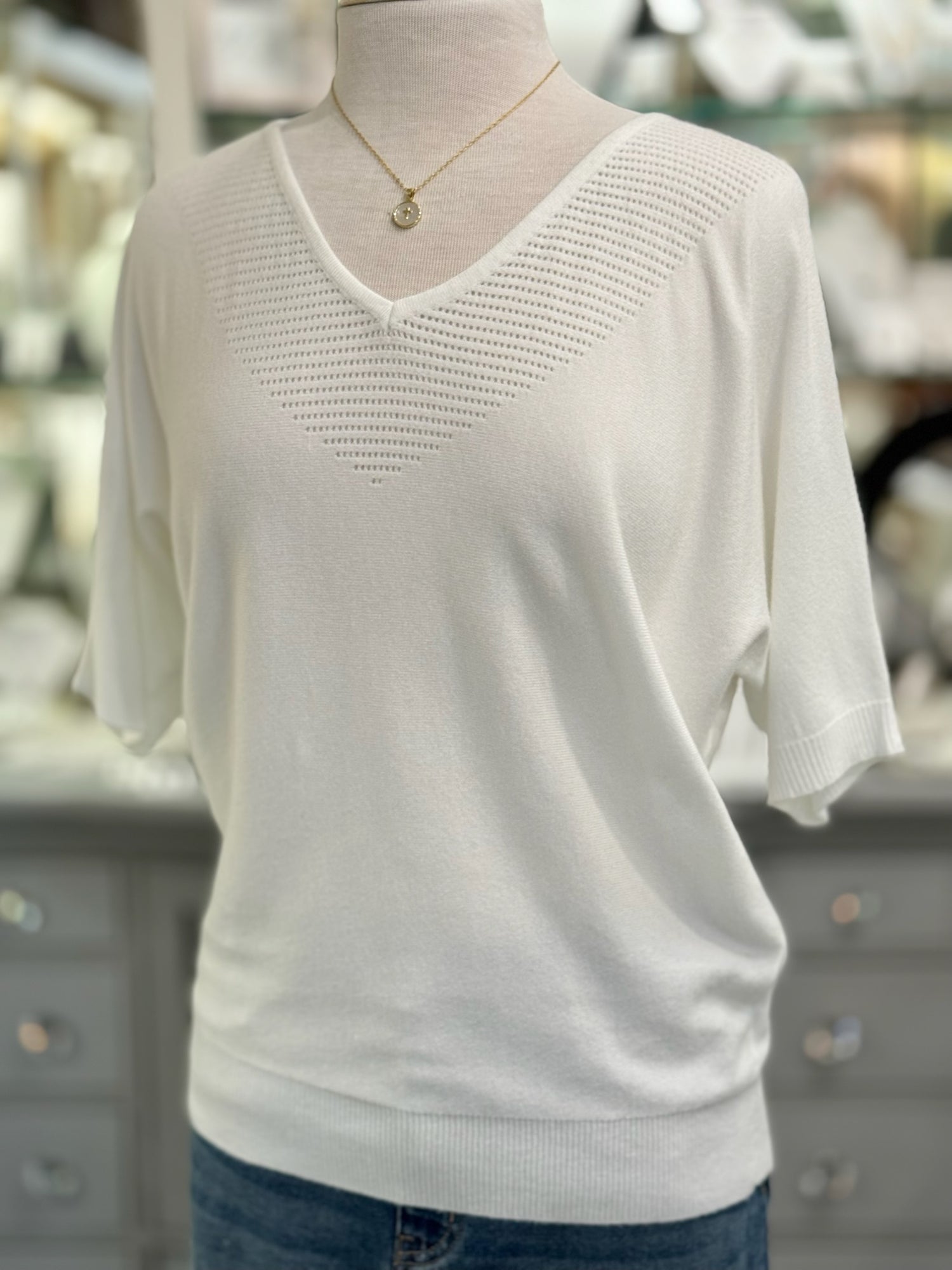 White knit top on a mannequin with a blurred background