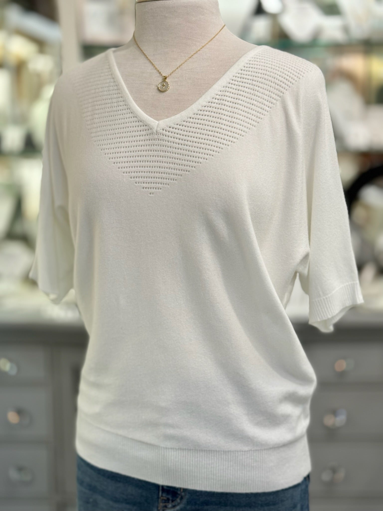 White knit top on a mannequin with a blurred background