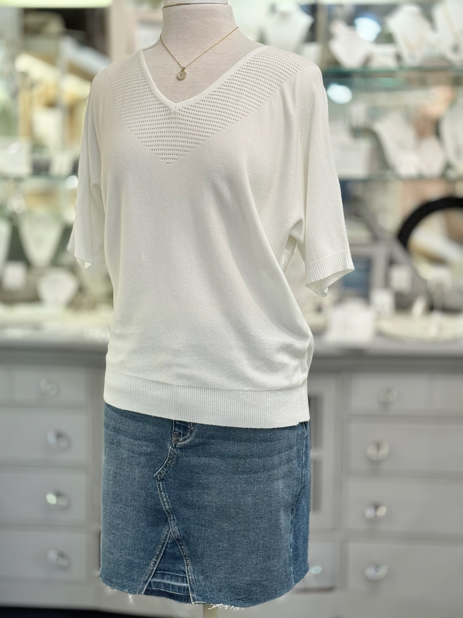 Mannequin wearing a white sweater and blue denim skirt in a store setting