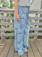 Person wearing blue leaf-patterned pants standing on a wooden deck.
