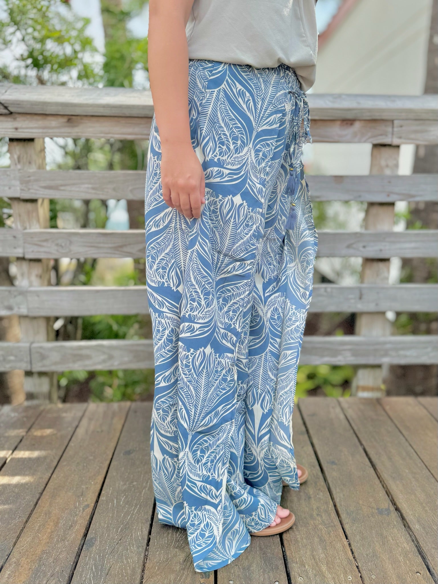 Person wearing blue leaf-patterned pants standing on a wooden deck.