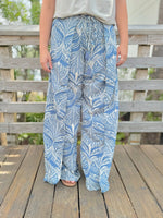 Person wearing blue and white patterned pants standing on a wooden deck.
