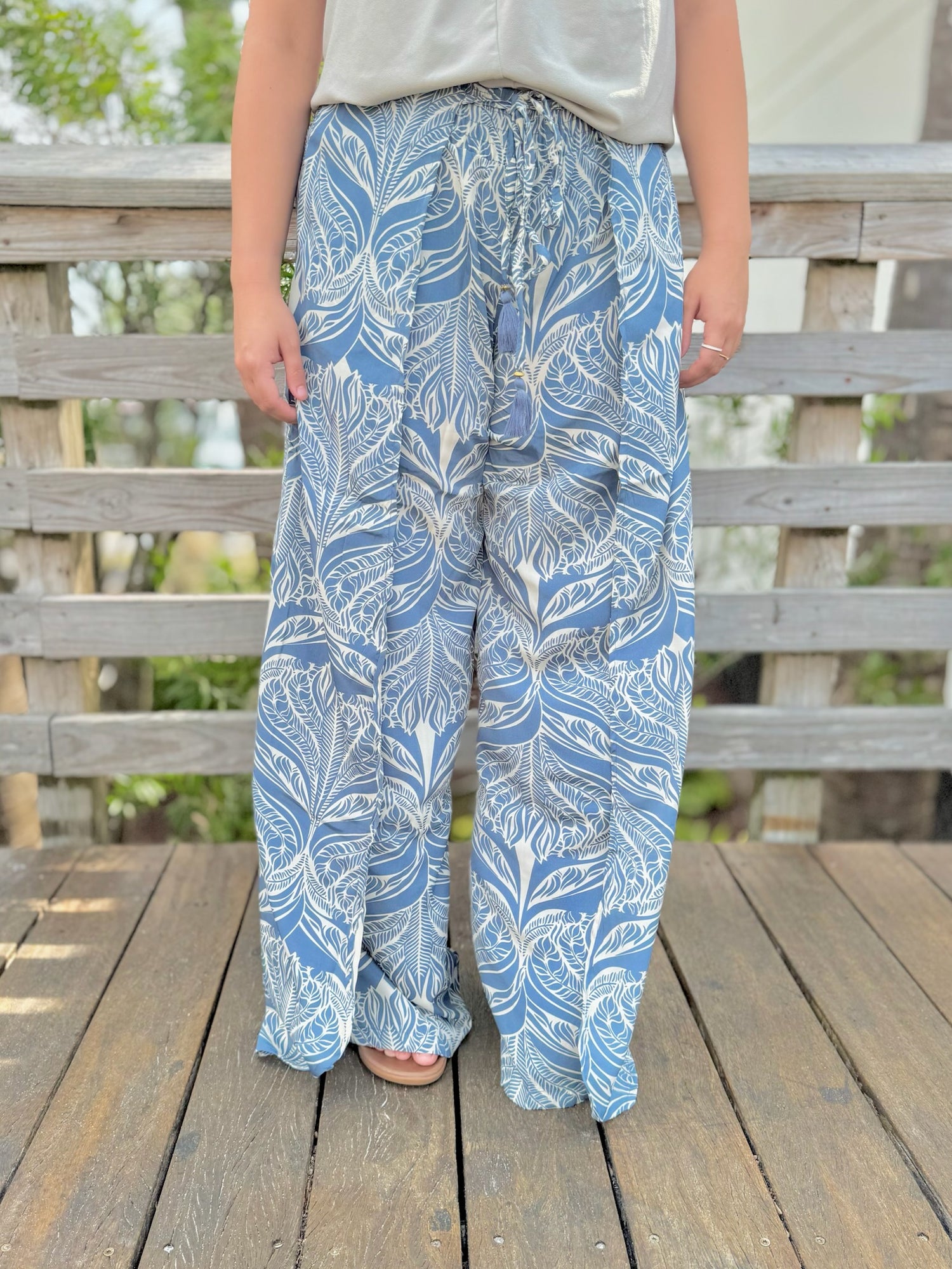 Person wearing blue and white patterned pants standing on a wooden deck.