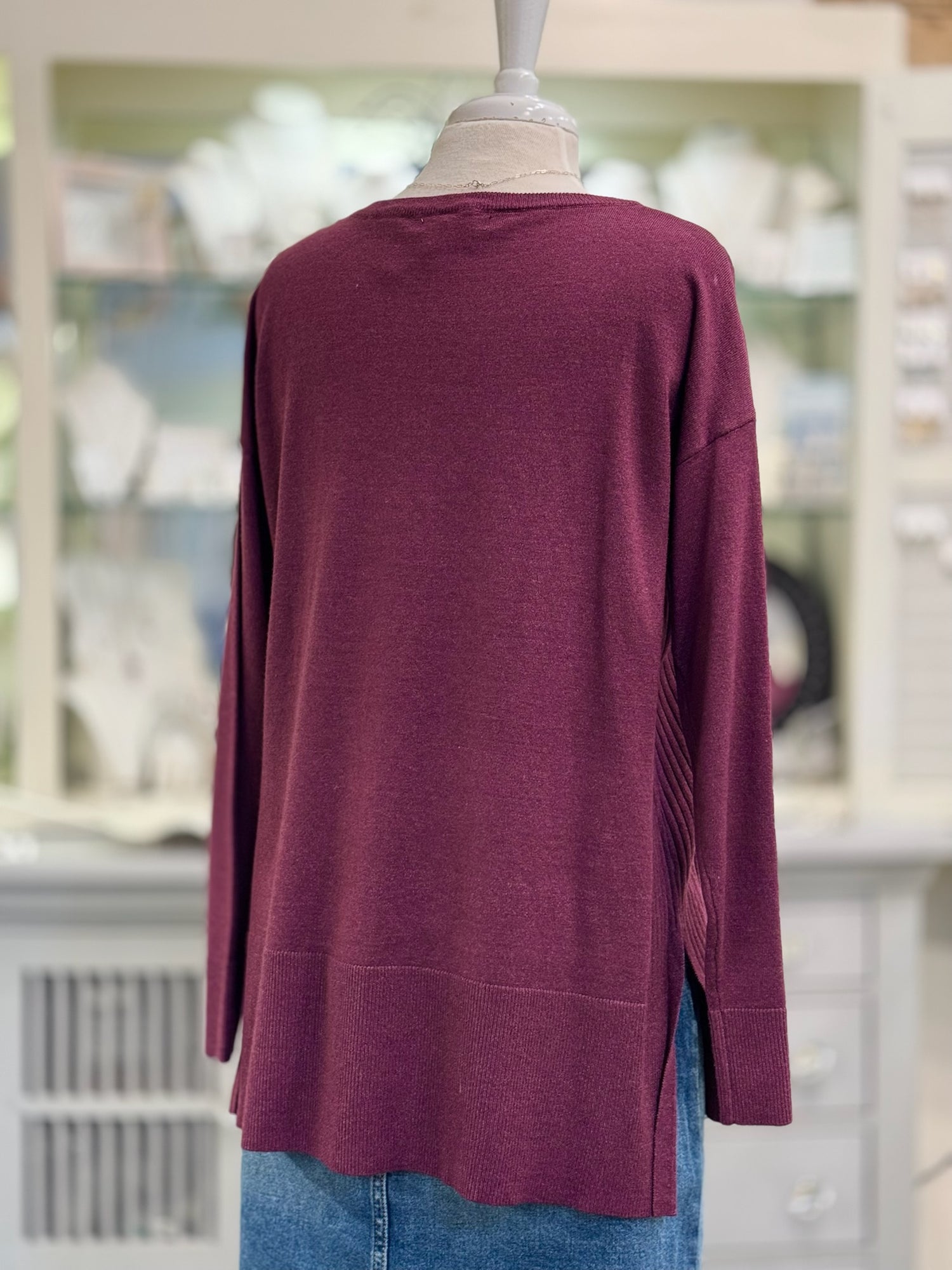 Maroon sweater on a mannequin with a blurred indoor background