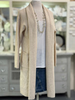 Mannequin wearing a beige cardigan over a white shirt and blue jeans in a store setting.